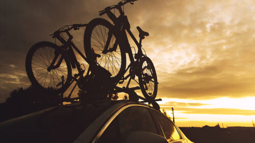 Bike Transportation – Two Bikes On The Roof Of A Car Against A B